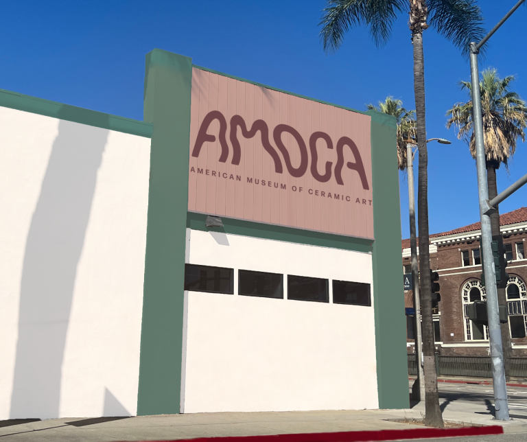 White building facade with green trim and Red sign saying AMOCA